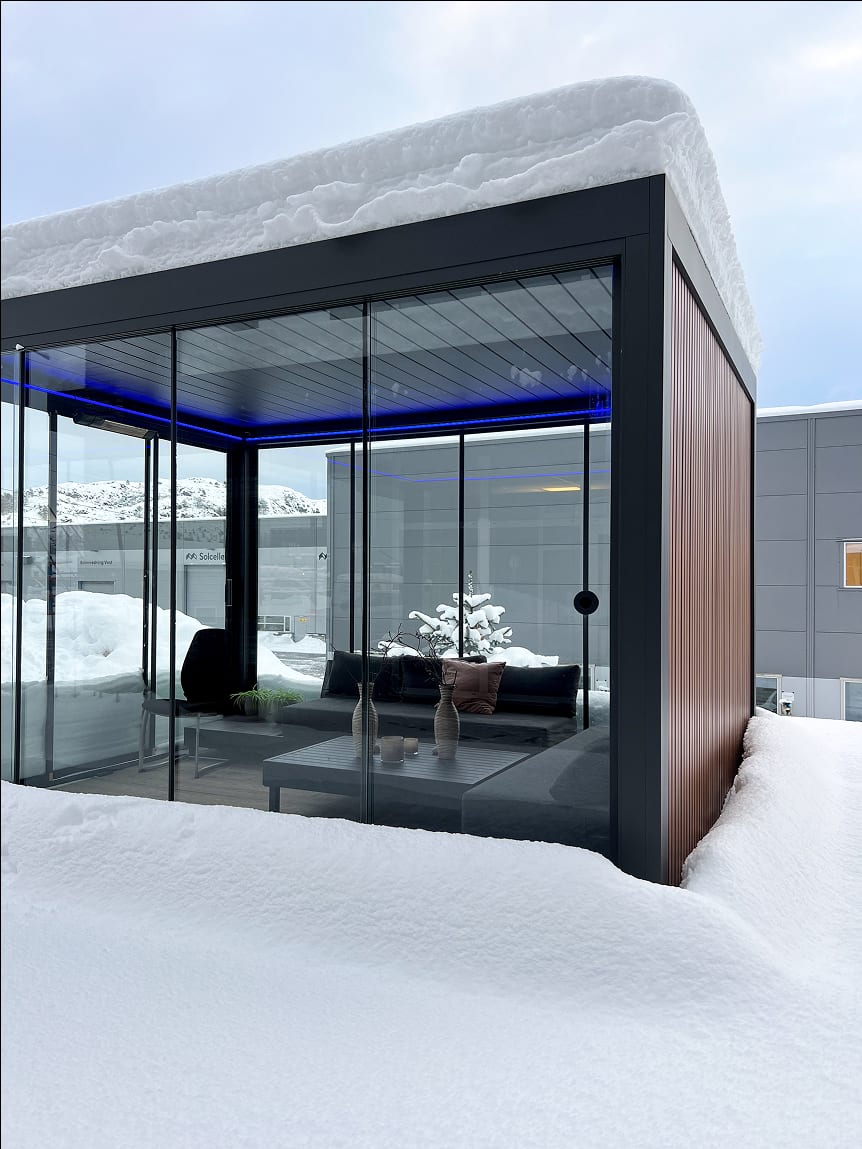 Terrasse fermée avec paroi vitrée et store vertical PERGOLUX, lampe chauffante allumée, soirée d'hiver conviviale en famille
