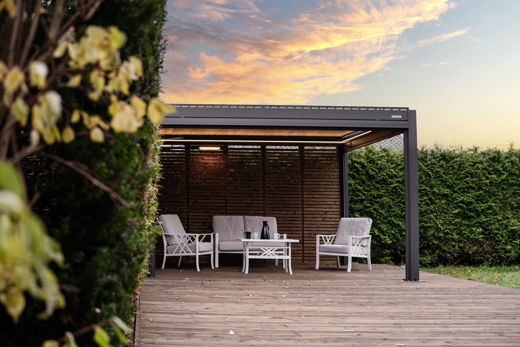 Pergola 4 Pro motorizzata con LED in grondaia accesi al tramonto su un terrazzo italiano, lamelle a 45 gradi aperte