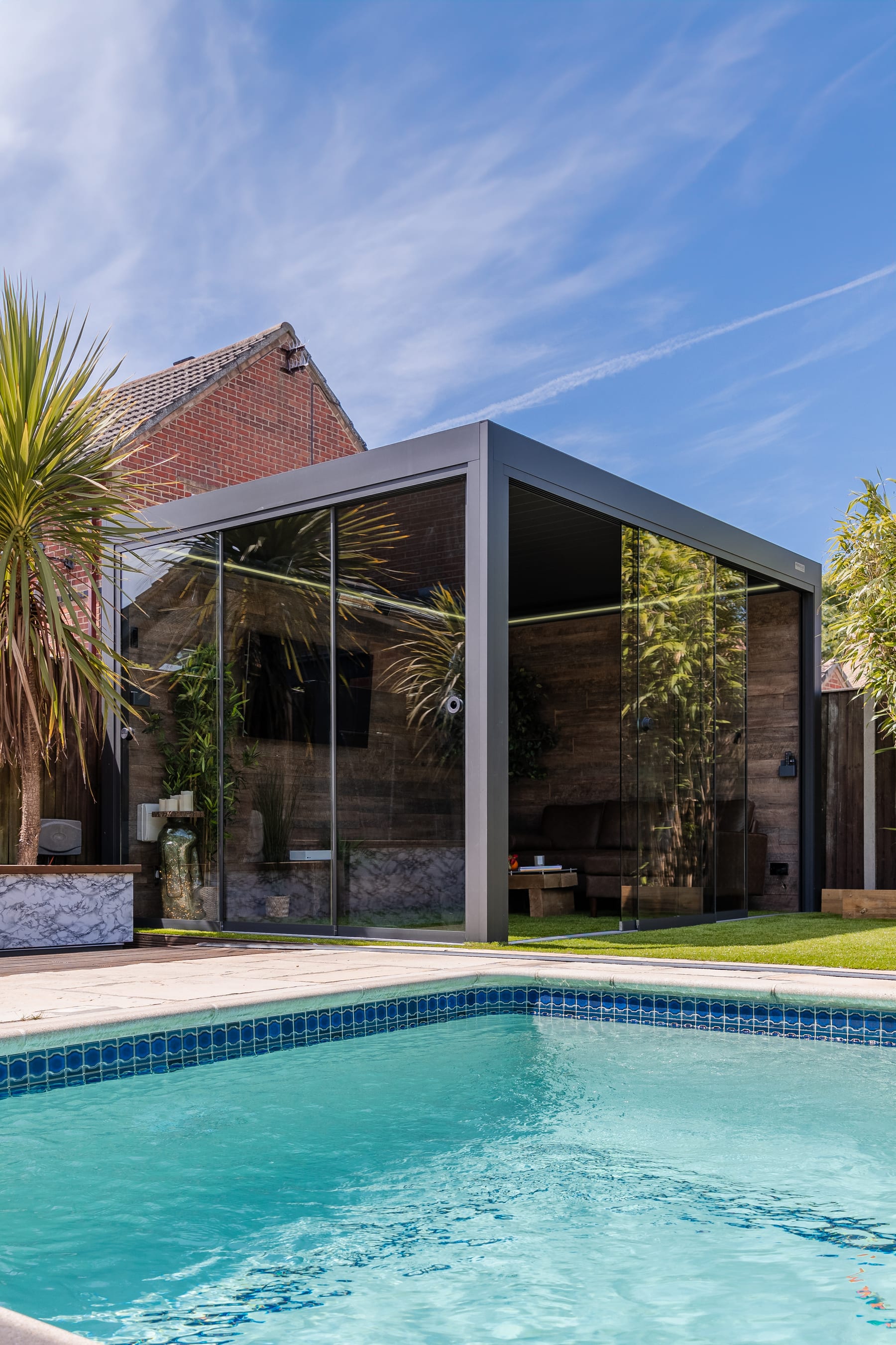 Freestanding PERGOLUX aluminium pergola with solid footplates bolted to a concrete patio in a coastal British garden