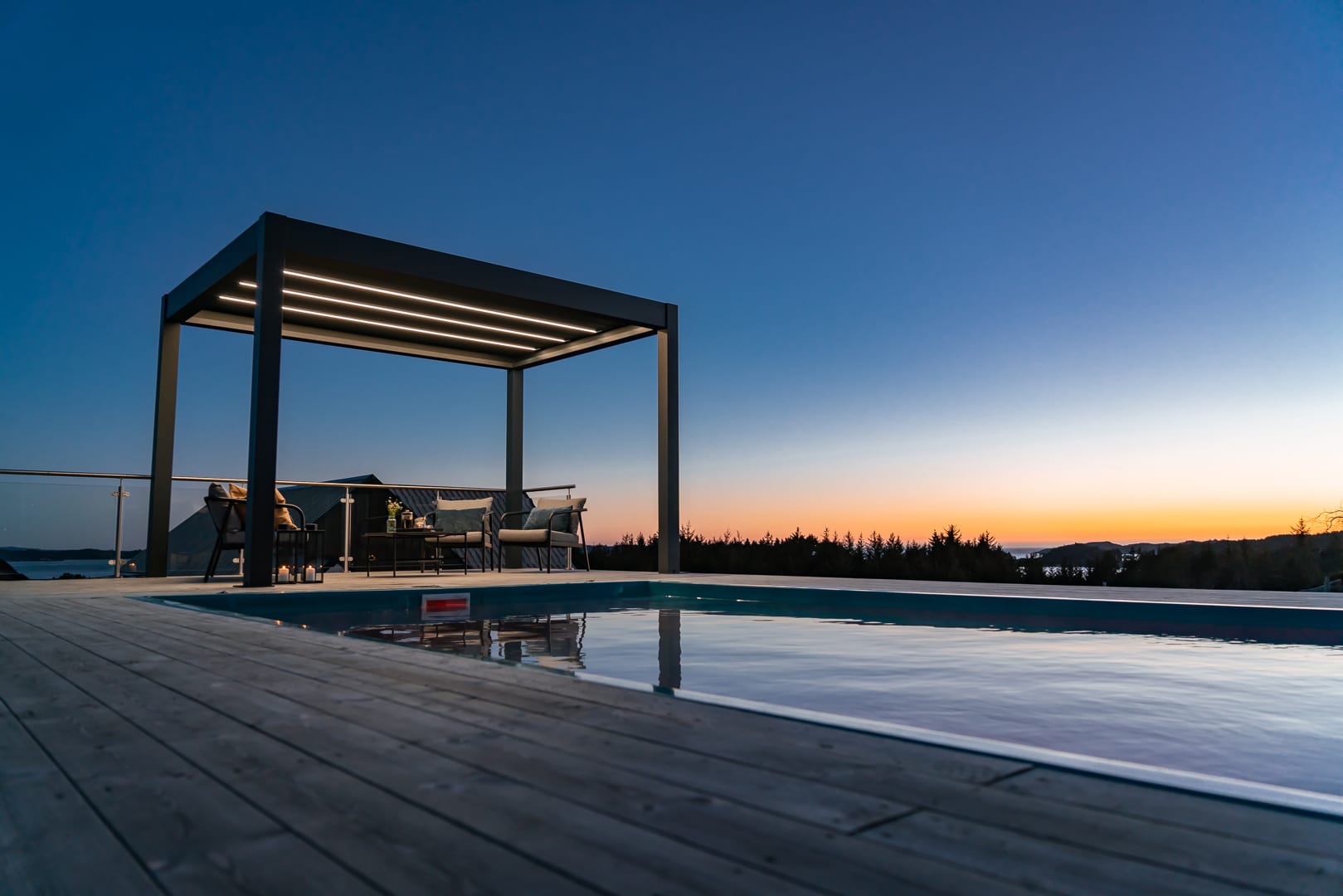 Lames de pergola bioclimatique en aluminium inclinées à 130 degrés filtrant la lumière rasante d'un soleil de fin d'après-midi estival
