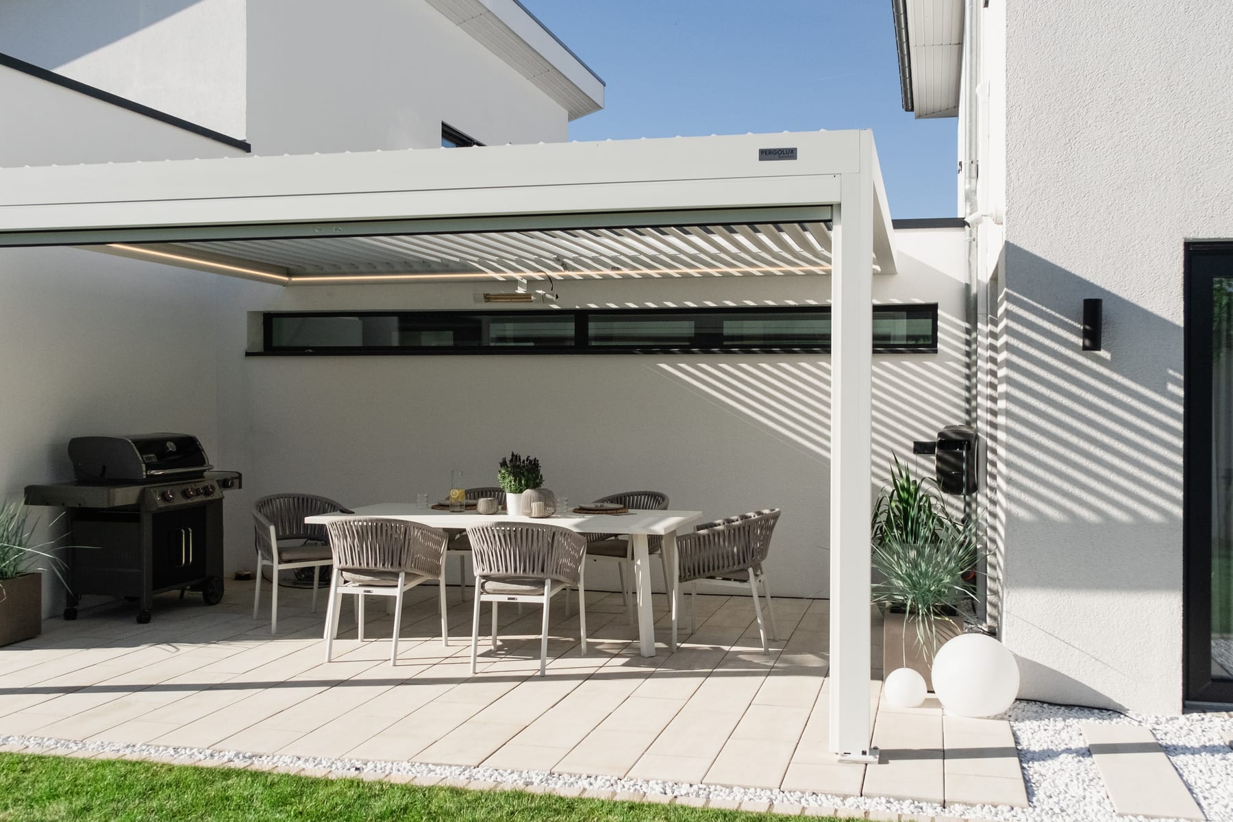 Outillage posé sur une terrasse en bois : perceuse, niveau à bulle et clé à crochet, boîte de vis PERGOLUX ouverte à côté