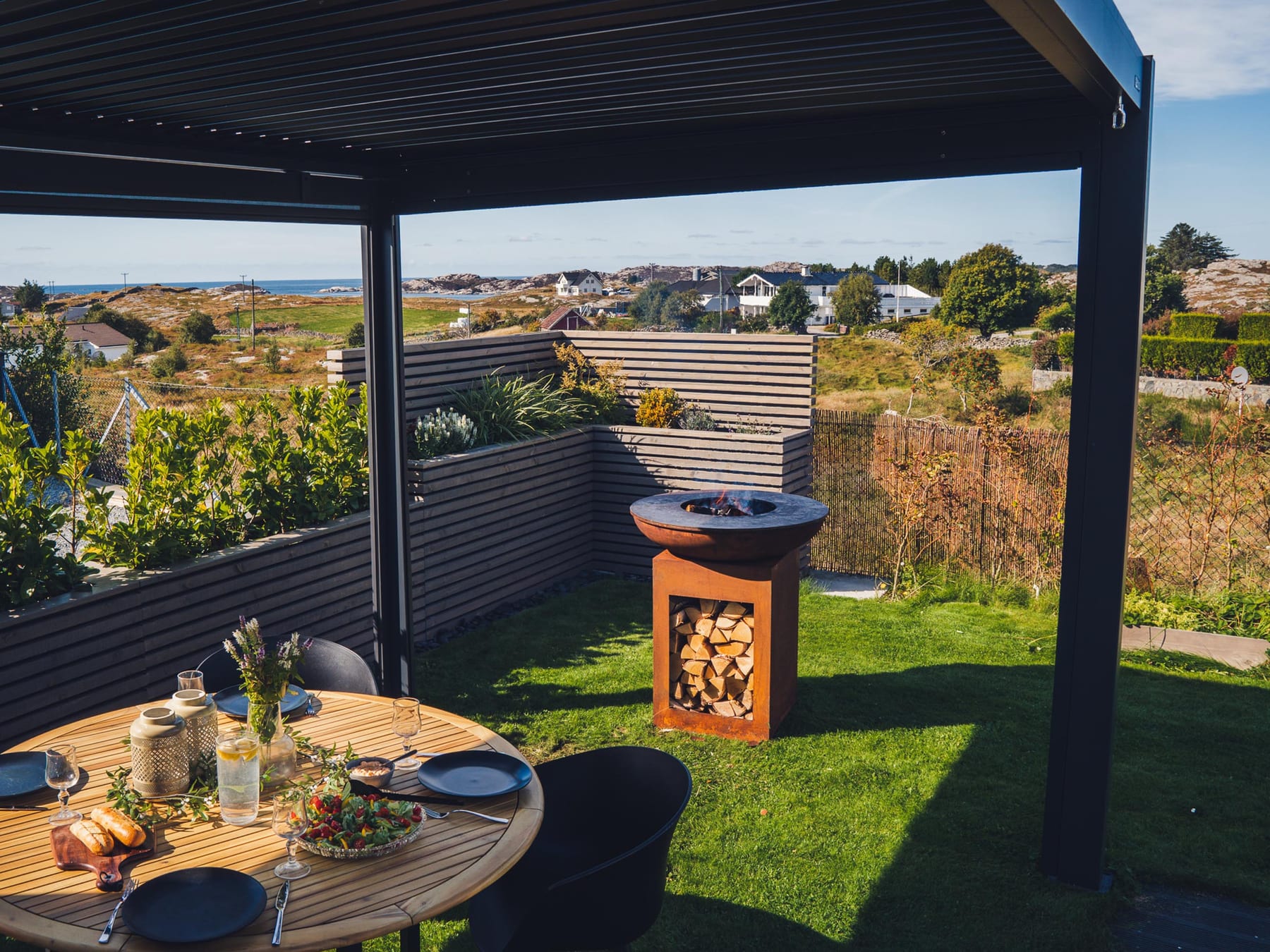 Pergola 4 Pro Max med 6 m søjlefrit spænd over en bred terrasse med spisebord og otte stole