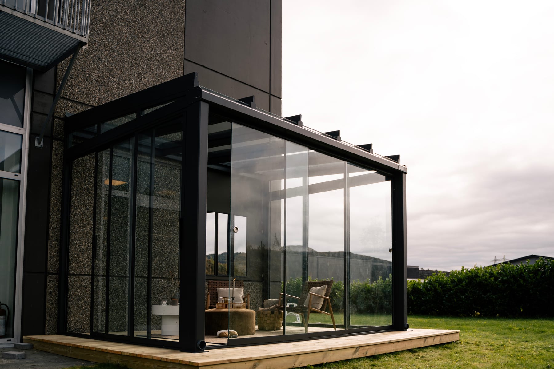 Détail d'une platine aluminium 200×200 mm vissée sur dalle béton sous un poteau de pergola autoportante en aluminium anthracite