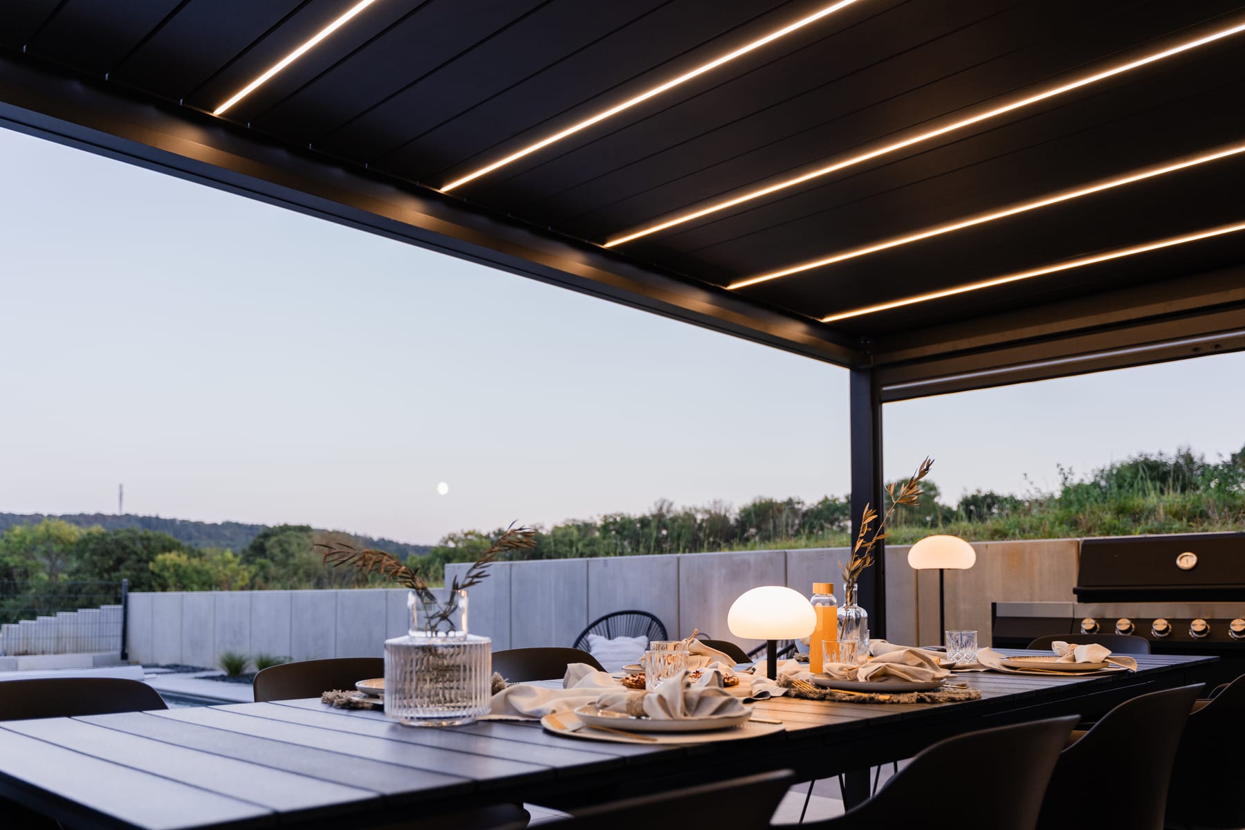 Short-throw projector mounted on a pergola beam casting a 100-inch image onto a retractable outdoor screen in a UK garden