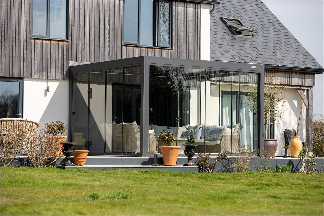 Pergola 4 Pro installed in a UK garden with Glass Walls accessory panels, showing full enclosed configuration for year-round use