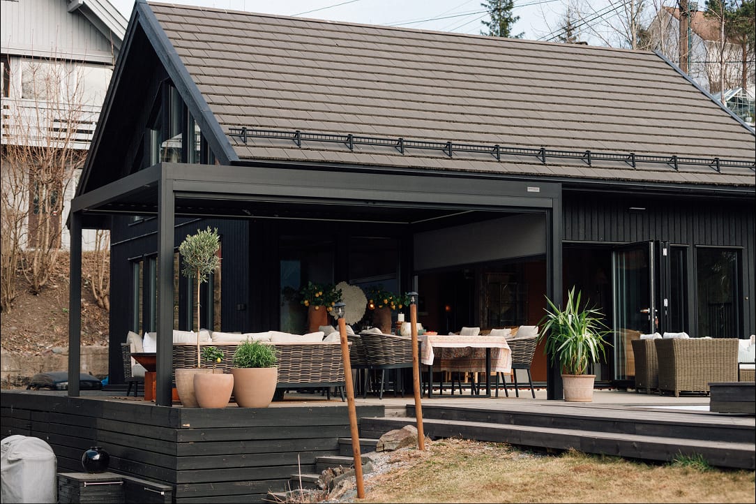 Homme mesurant la hauteur d'une façade avec un mètre ruban, terrasse adossée à une maison de style provençal