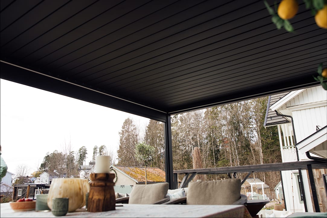 Propriétaire mesurant une terrasse avec un mètre ruban, carnet de notes avec schéma de pergola et dimensions annotées
