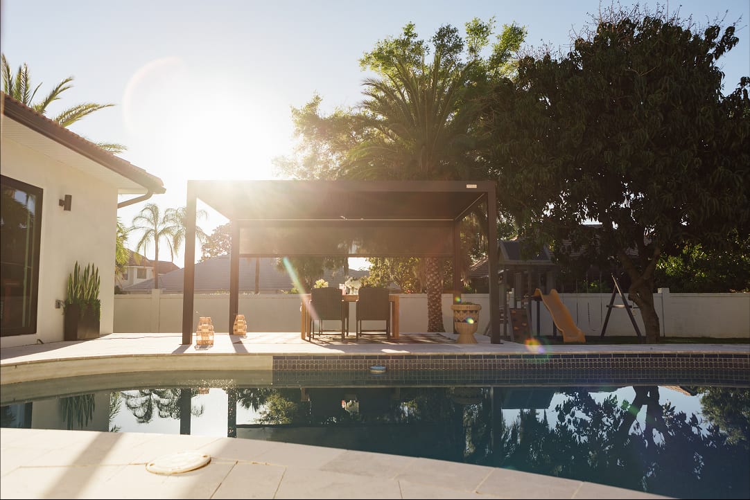 Pergola 4 Pro installée face à une côte atlantique venteuse, poteaux scellés dans dalle béton, paroi vitrée montée côté vent