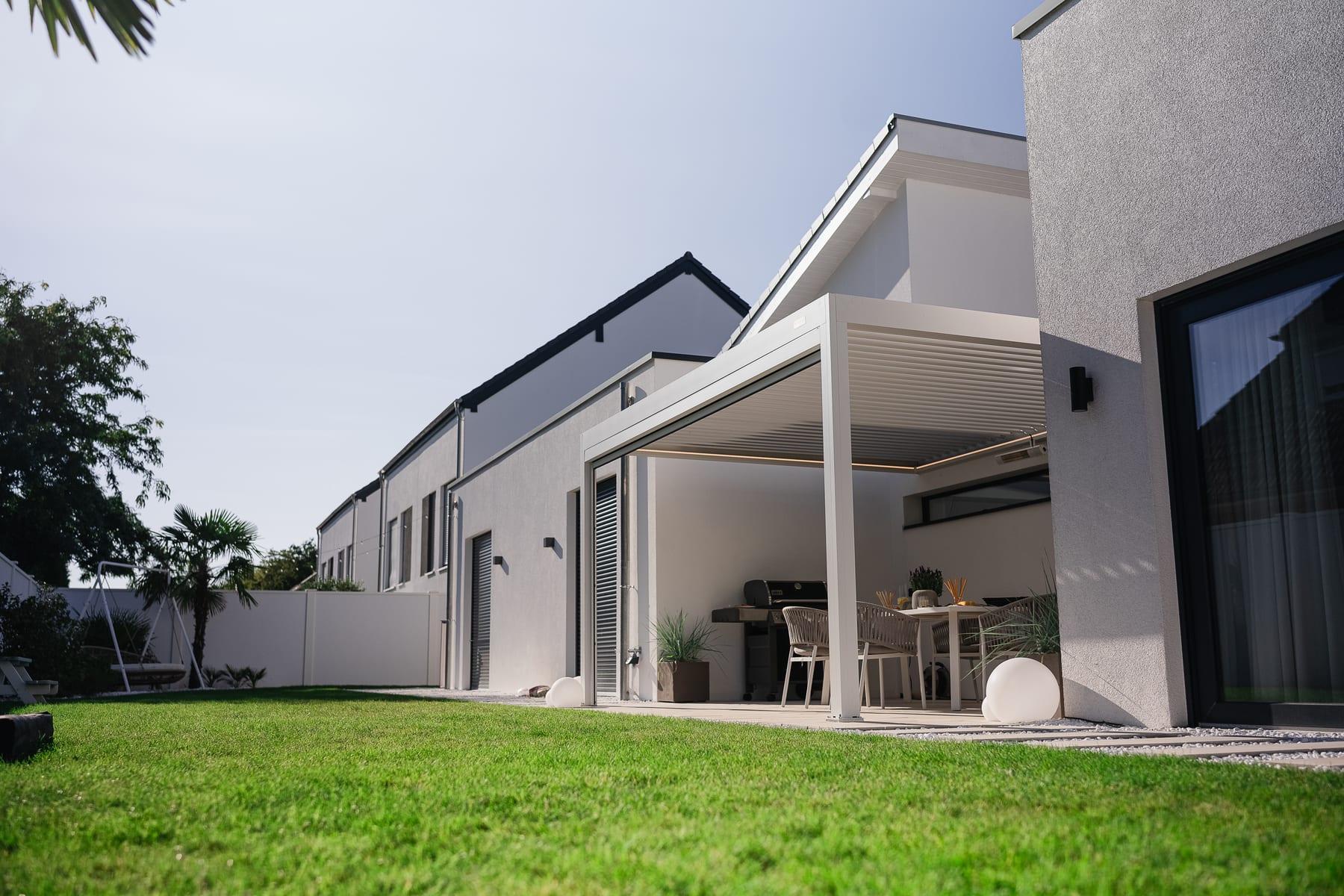 Mesa com calculadora e rascunho de comparativo de custos de pérgola ao lado de catálogo de materiais, luz natural de escritório em casa