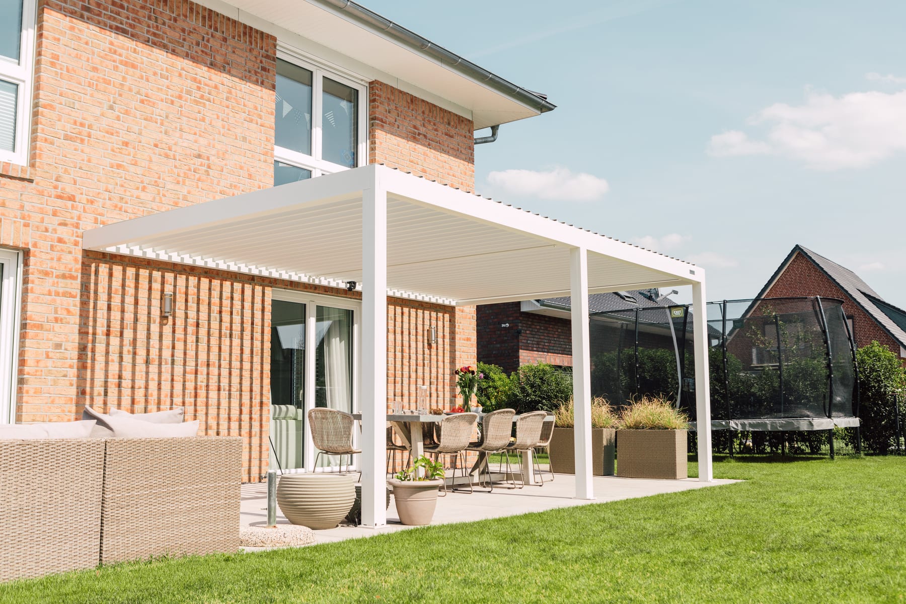 Smartphone affichant une interface de paiement fractionné Alma sur fond de terrasse avec pergola aluminium