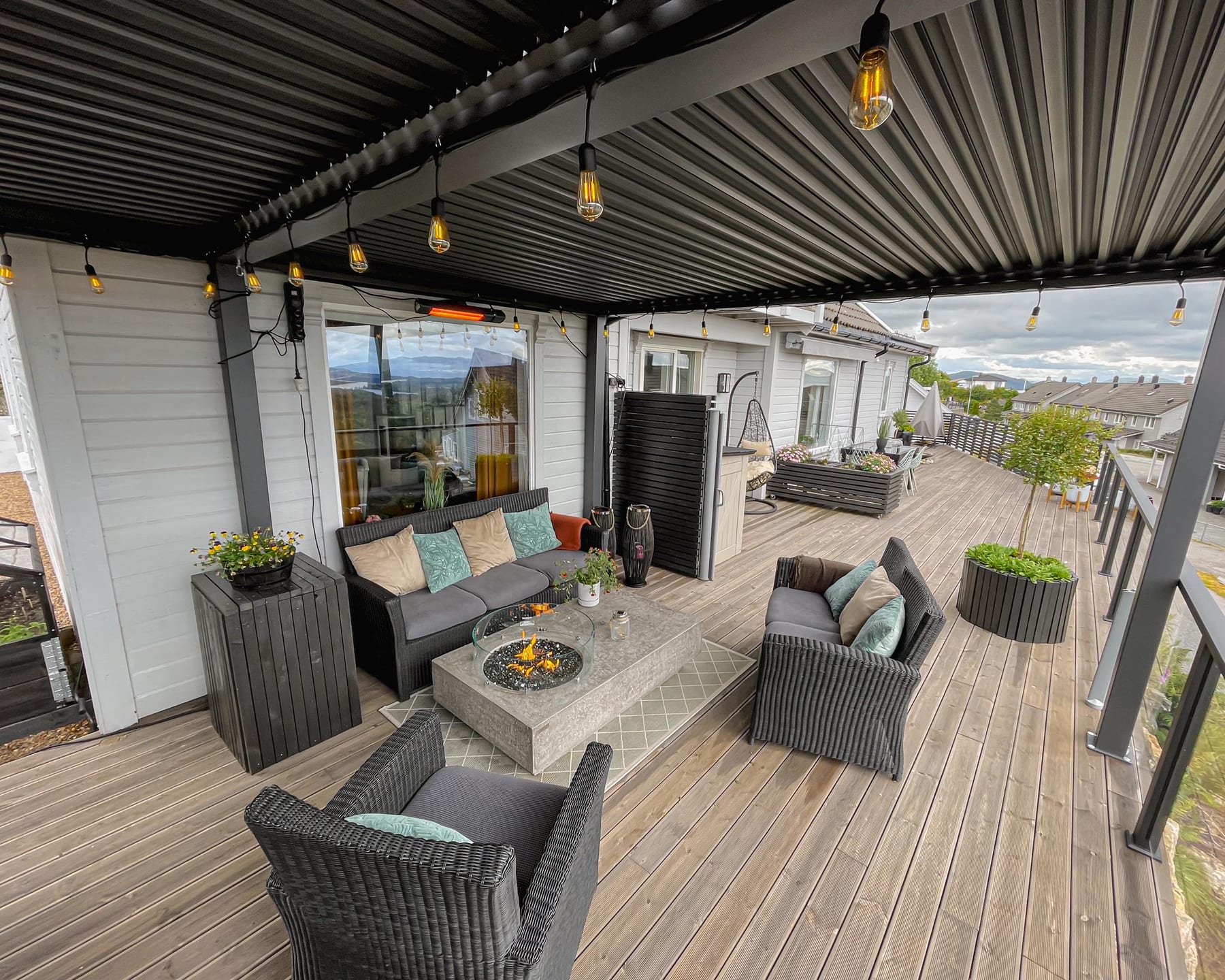 Pergola équipée de stores verticaux et d'une lampe chauffante, groupe de personnes autour d'une table en soirée d'automne