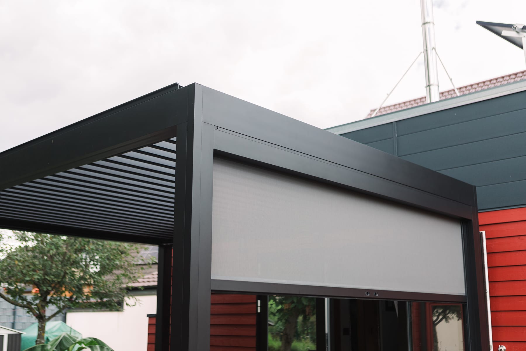 Gros plan sur lames de pergola aluminium en position mi-ouverte à 45°, lumière du matin filtrant en diagonale sur une terrasse