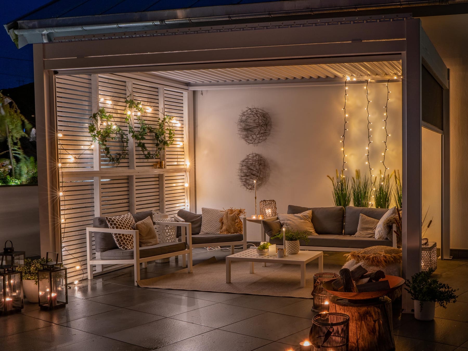 Main tenant un smartphone avec l'application de contrôle de pergola ouverte, terrasse motorisée en arrière-plan sous un ciel changeant