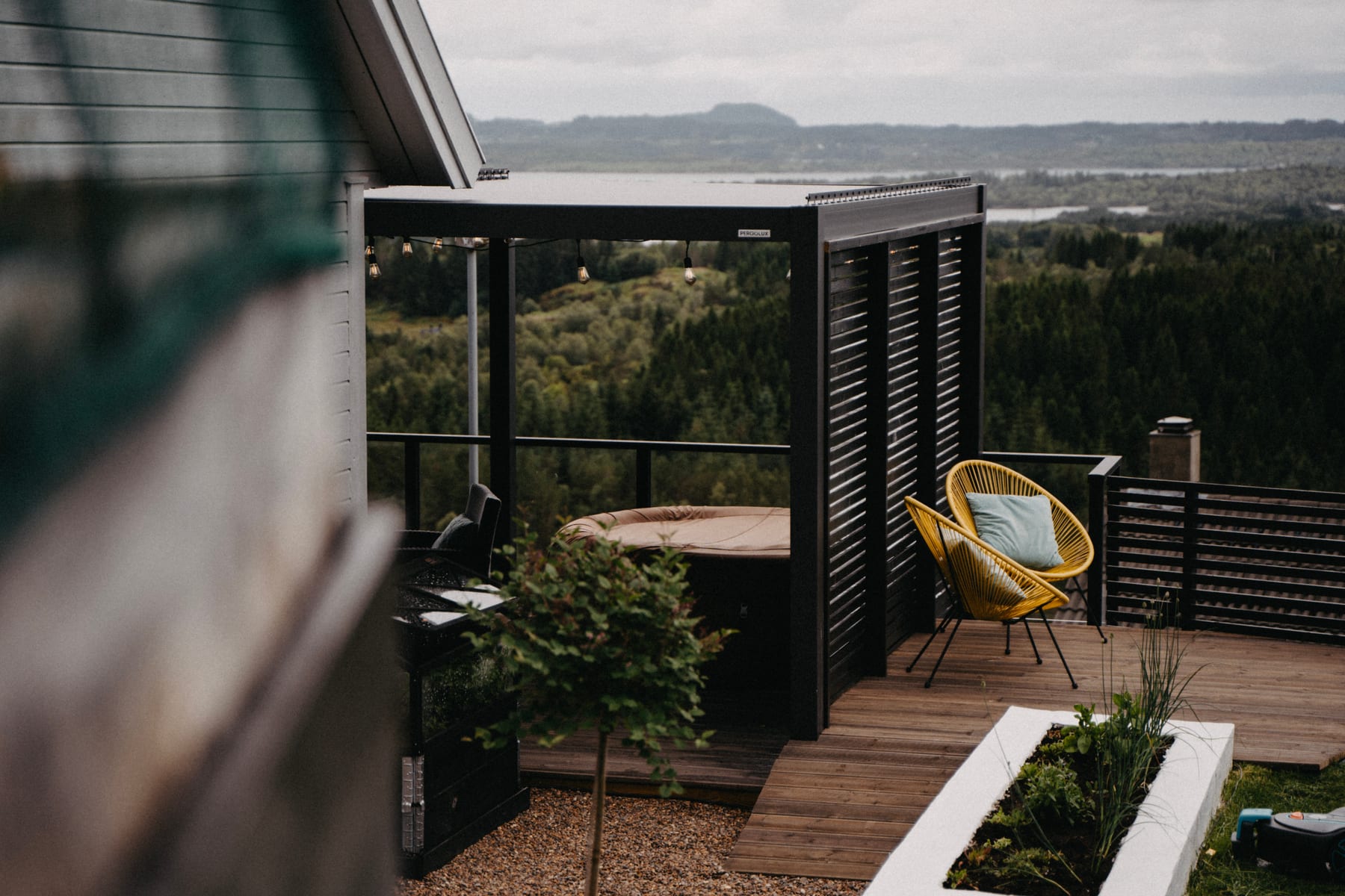 Terrasse de résidence secondaire française en automne, pergola fermée à lames horizontales, chaises de jardin vides sous lumière dorée