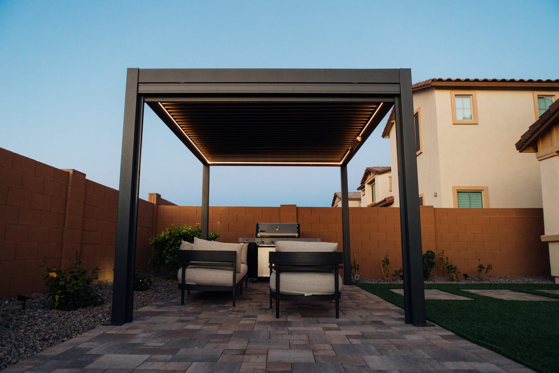 Pergola 4 Pro gutter-integrated RGB LED strip glowing warm white around a garden pergola perimeter at night, projector screen visible