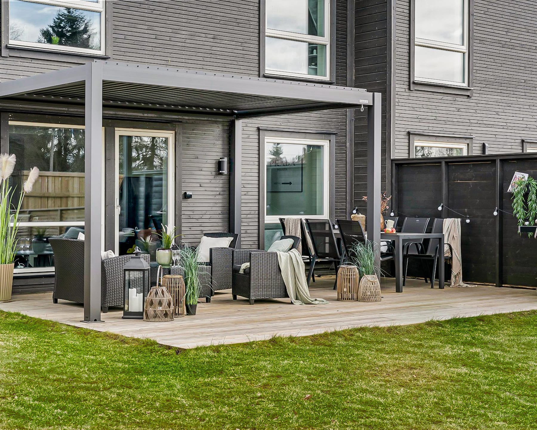 Terrasse vue de côté avec trois personnes stabilisant un poteau de pergola pendant la fixation des platines au sol bétonné